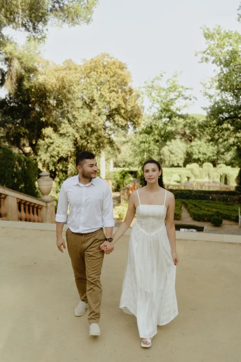 Couple walks hand in hand through a sunlit garden, captured during a couples & engagements photography session.