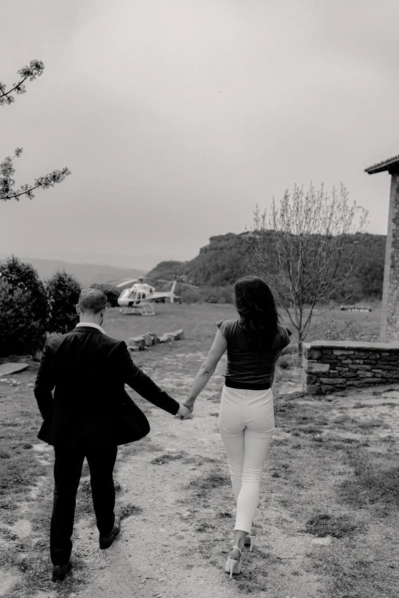 Couple walks hand in hand toward a waiting helicopter, capturing anticipation before their countryside surprise proposal sess