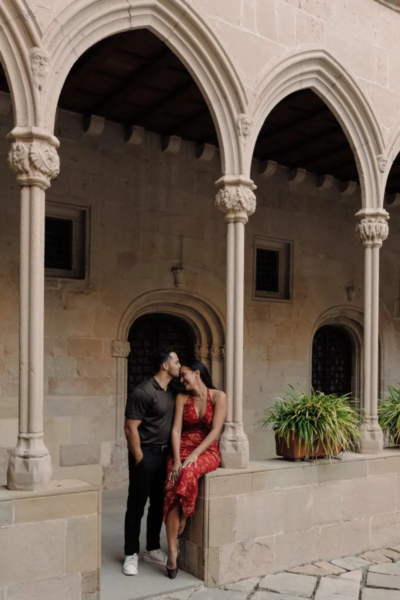 Dan and Sydney embrace in a symmetrical portrait beneath the monastery arches.