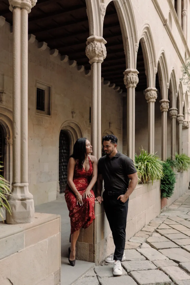 Dan and Sydney share a playful moment beside the columns of a quiet Montserrat cloister.