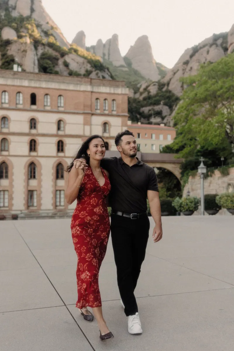 Dan and Sydney walk arm in arm through the open square at Montserrat monastery.