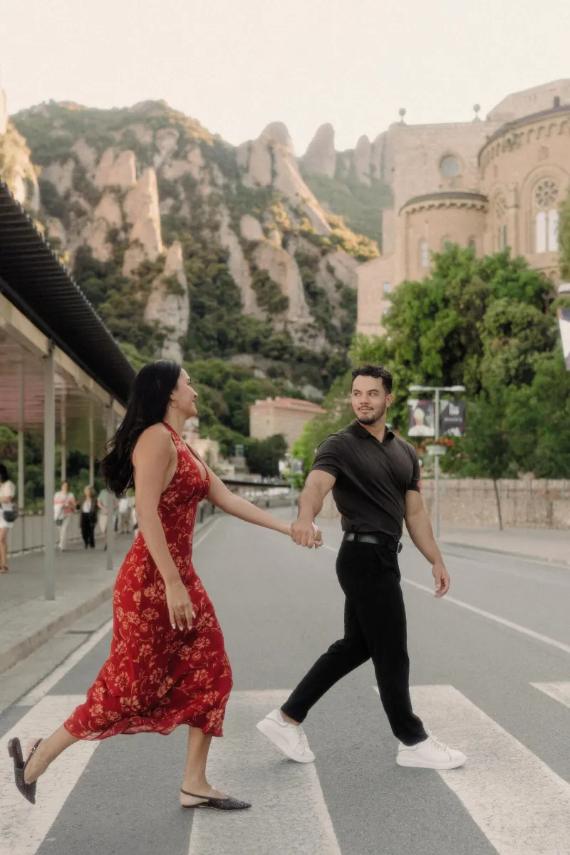 Dan and Sydney walk hand in hand across a quiet road in the Montserrat monastery complex.
