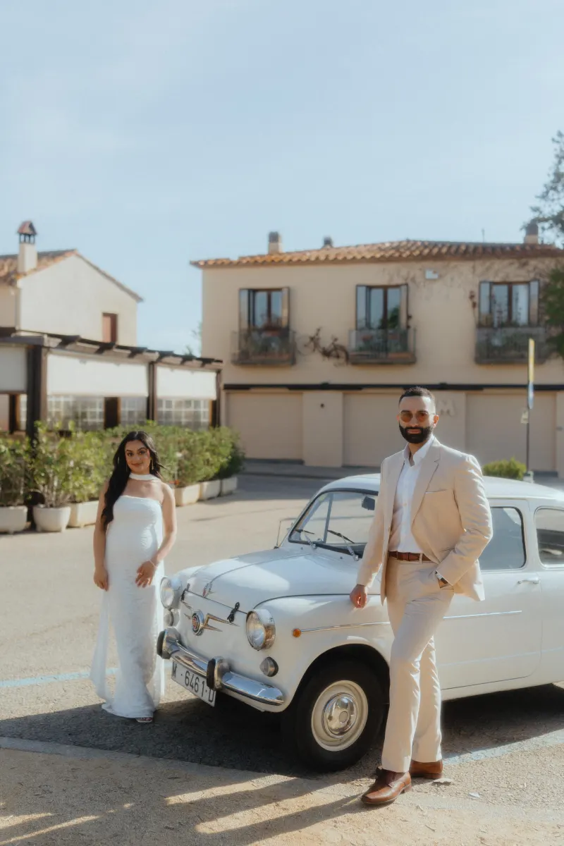 Elegant couple poses by a vintage car during a surprise proposal photoshoot in a charming Mediterranean village.