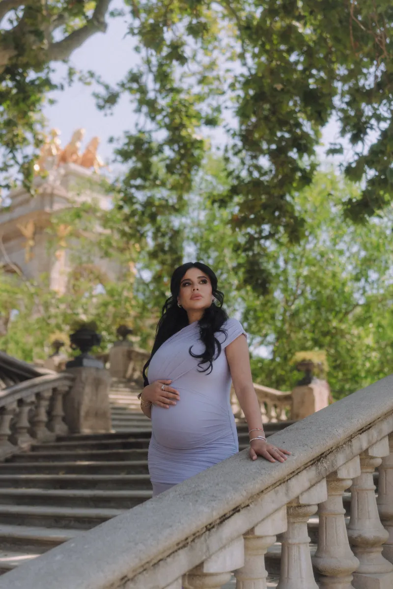 Elegant expectant mother in a lilac dress poses on historic stone steps, Vacation Portraits photoshoot in Barcelona.