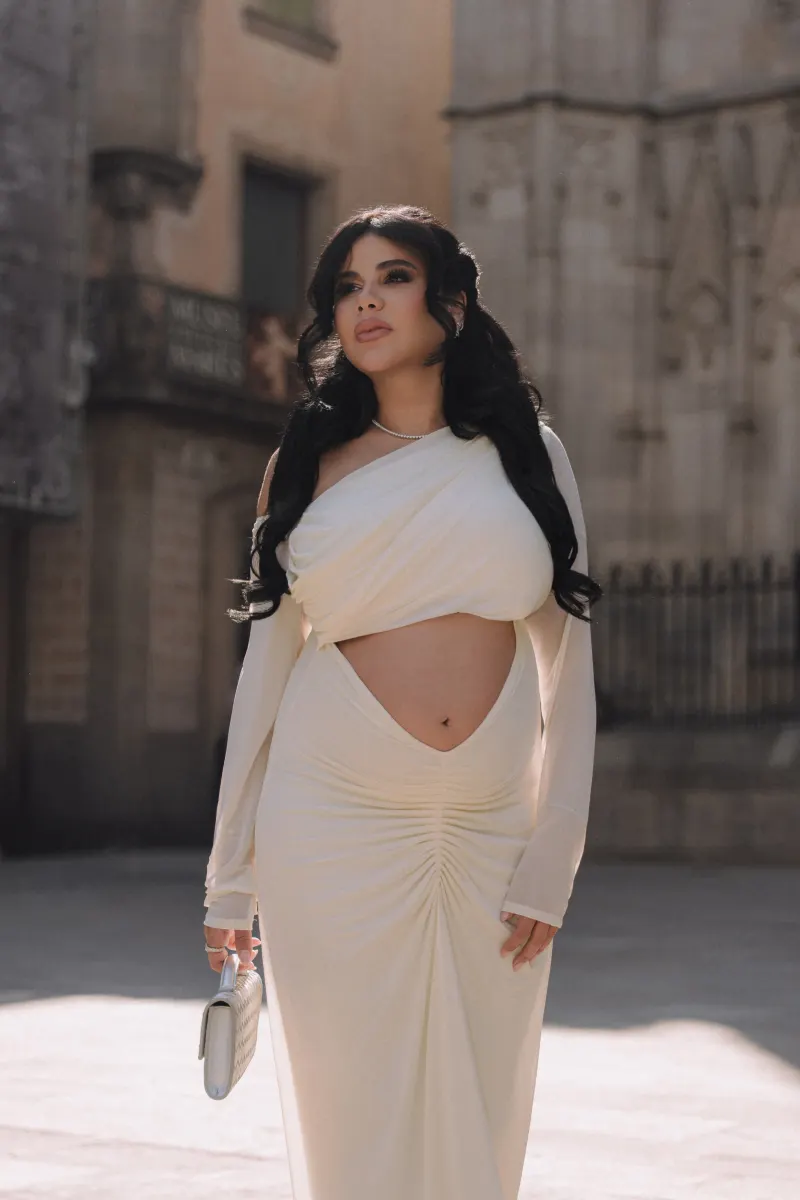 Elegant woman in a white dress poses confidently during a Vacation Portraits photoshoot in a historic city square.