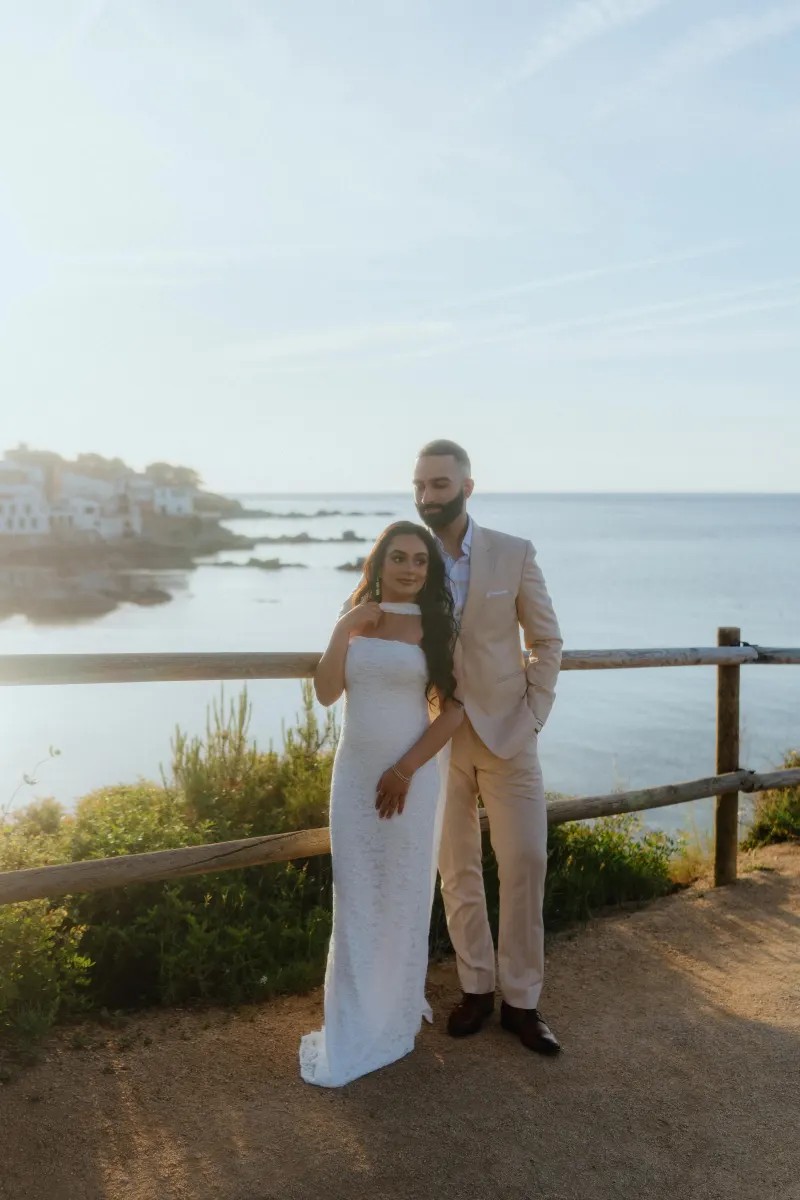 Engaged couple embraces by the seaside at golden hour, captured during a surprise proposal photoshoot.
