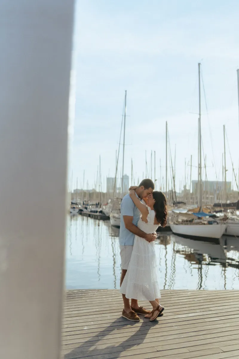 Engaged couple embracing on a marina boardwalk at sunset, captured during a couples & engagements photoshoot.