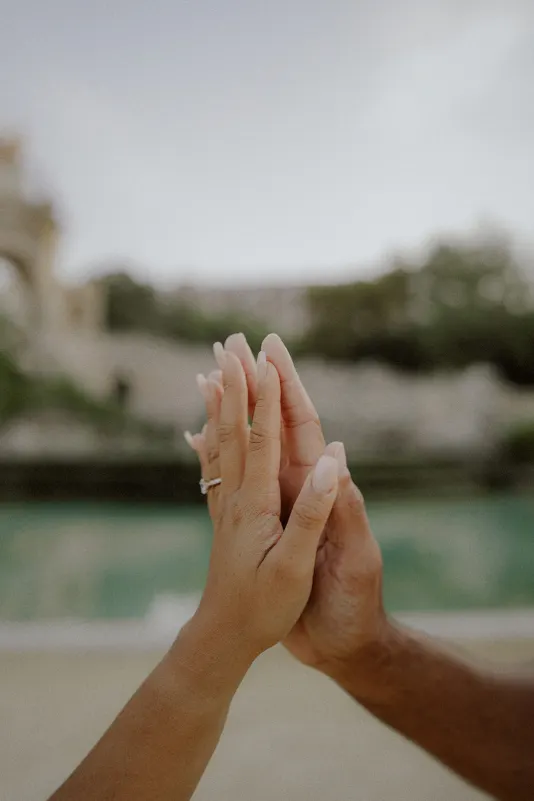 Engaged couple gently touching hands, highlighting the engagement ring during a couples photoshoot at Parc de la Ciutadella.