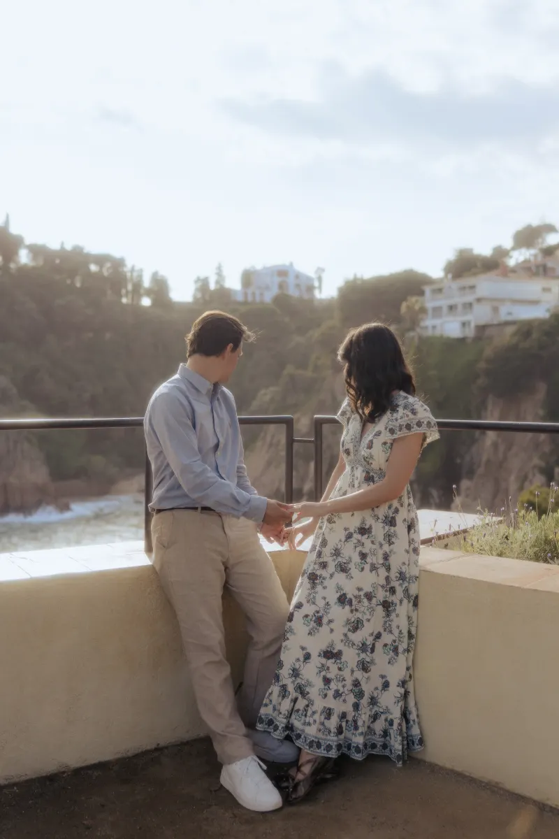 Engaged couple holds hands and shares a quiet, emotional moment after a surprise proposal photoshoot by the Mediterranean.