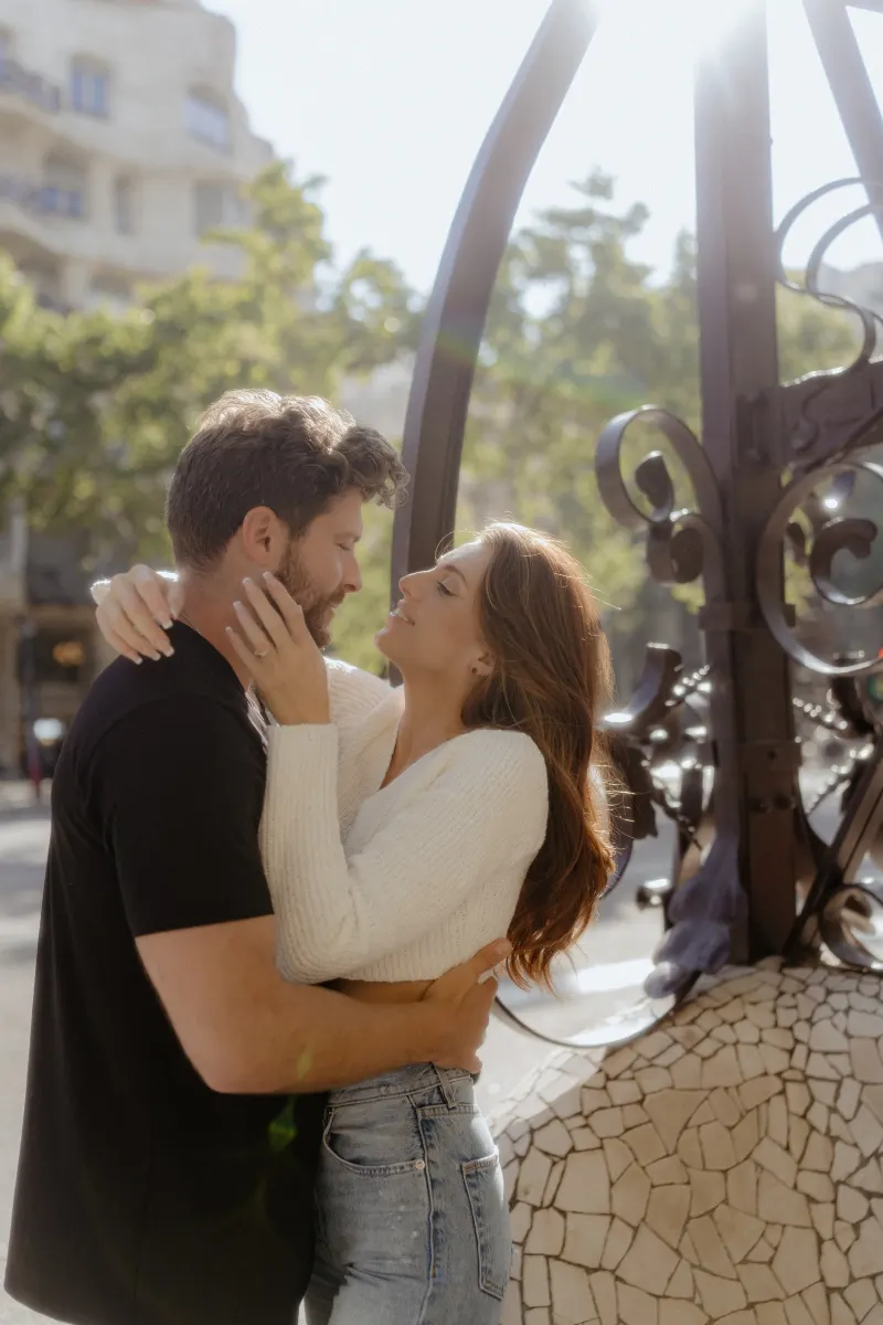 Engaged couple shares a loving embrace in the sunlight during a couples & engagements photoshoot in the city.