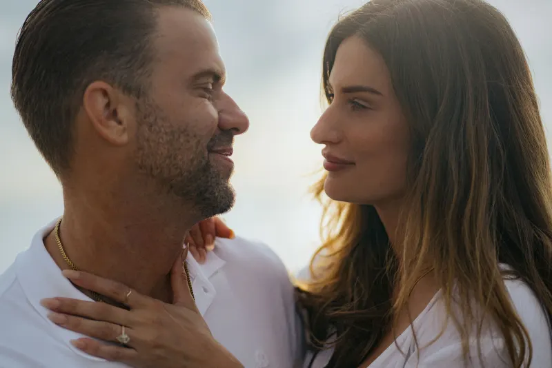 Engaged couple sharing a loving gaze on the beach, highlighting their connection during a couples & engagements photoshoot.