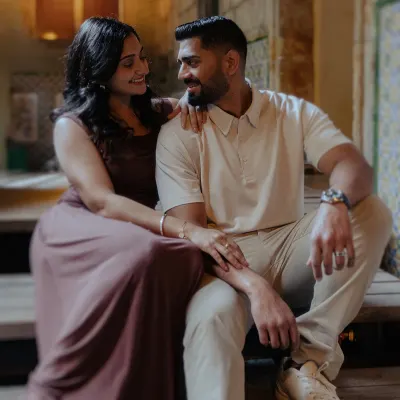 Engaged couple sharing a warm, intimate moment during a couples photoshoot in a cozy, softly lit setting.