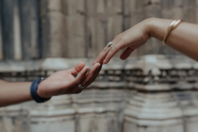 Engaged couple’s hands gently reaching for each other, highlighting a ring during a romantic couples photoshoot in the old ci