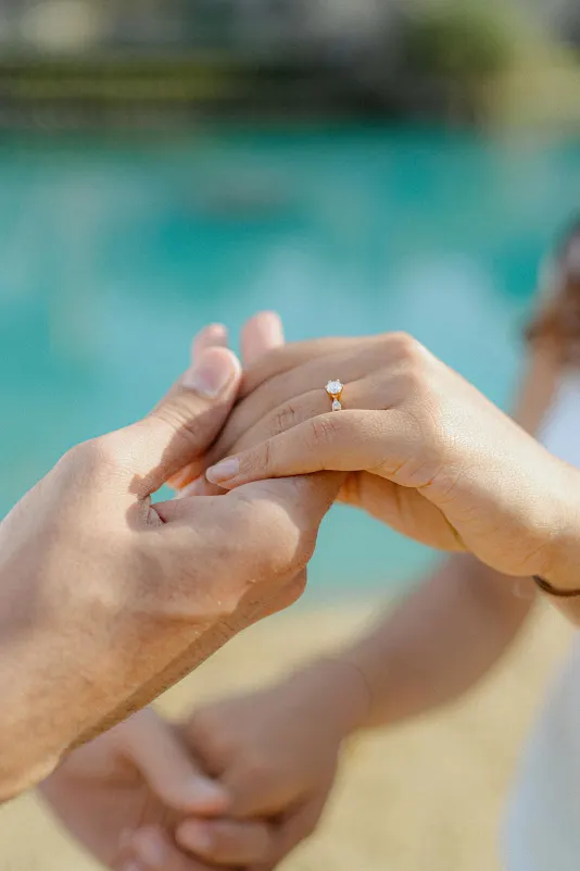 Hands intertwined as an engagement ring sparkles during a surprise proposal photoshoot by the water in Barcelona.