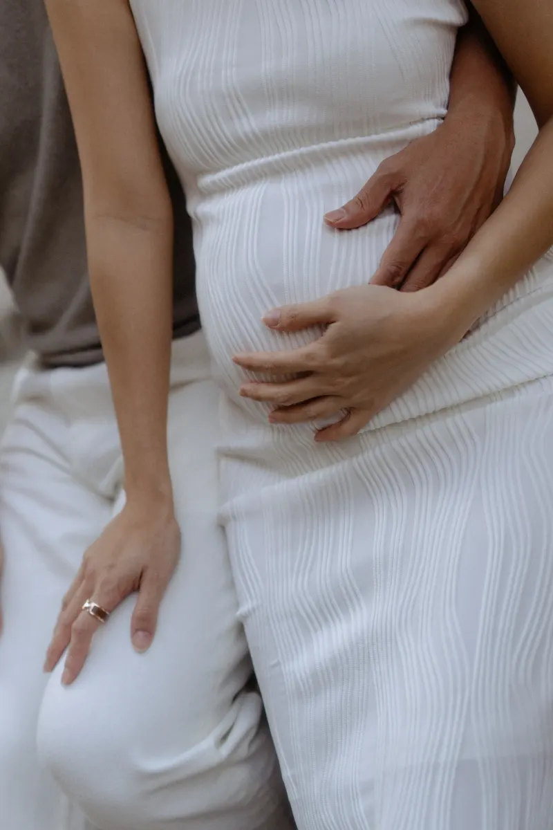Hands of an expectant couple gently resting on a baby bump during a Vacation Portraits photoshoot in Barcelona.