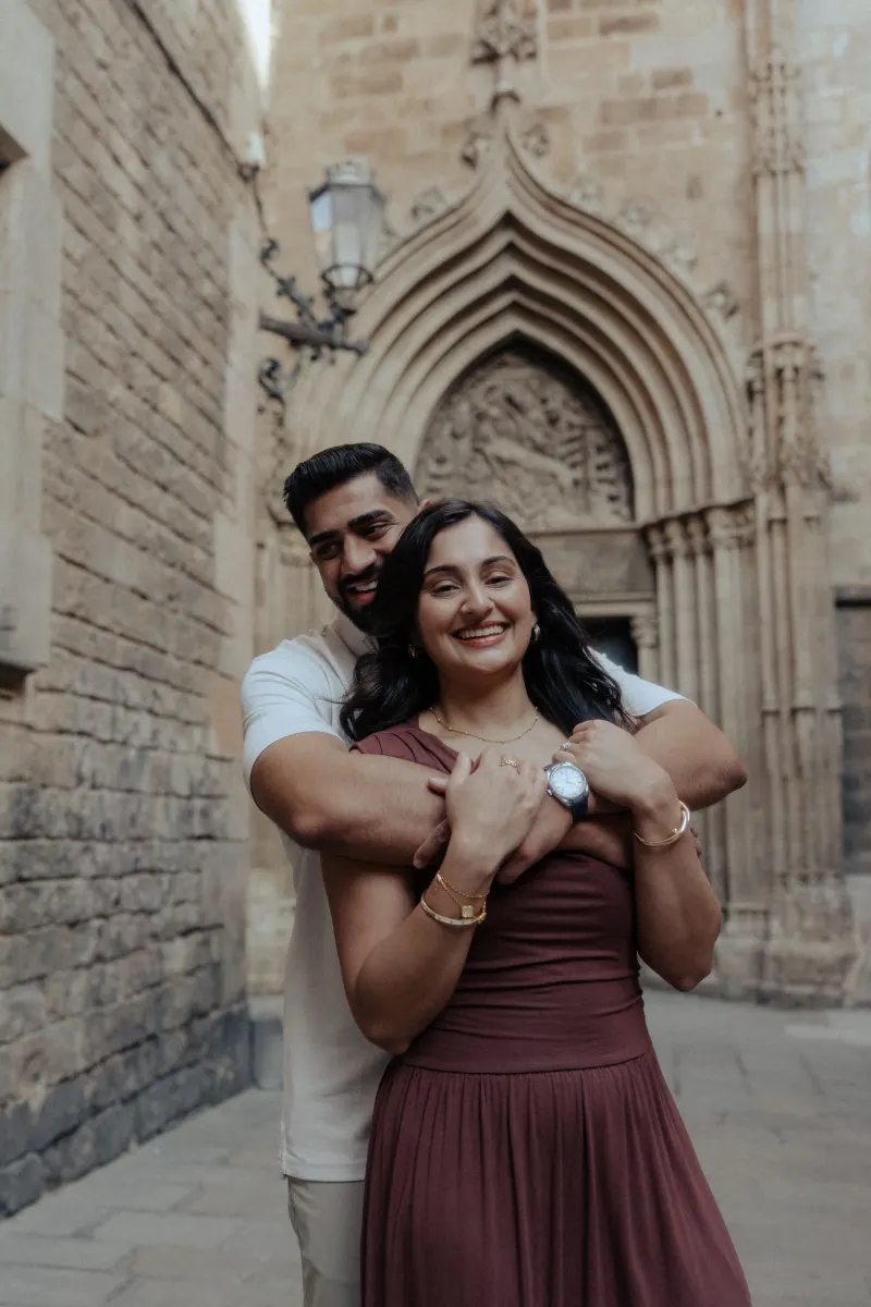 Happy couple embraces and smiles in a historic stone alley during a couples & engagements photoshoot.