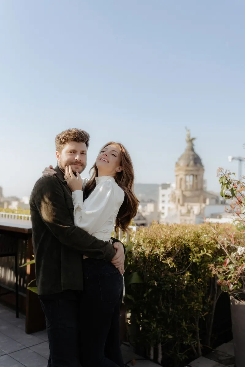 Happy couple embraces on a sunlit rooftop, sharing a romantic moment during a couples & engagements photoshoot.