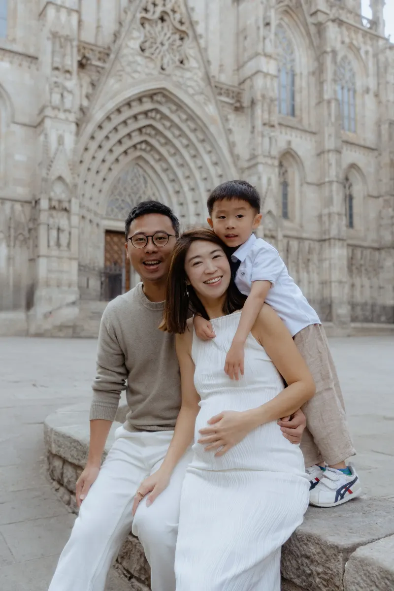 Happy family posing together during a Vacation Portraits session in front of Barcelona’s historic cathedral.