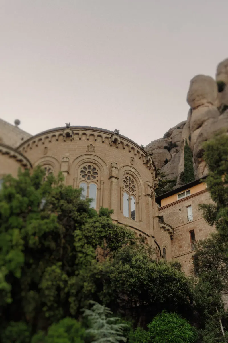 Historic monastery architecture and rounded Montserrat rock formations rise above spring greenery.