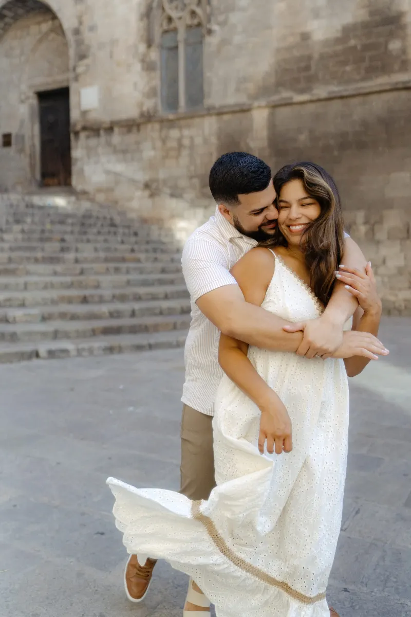Joyful couple embraces and smiles in front of historic stone steps during a couples & engagements photoshoot.