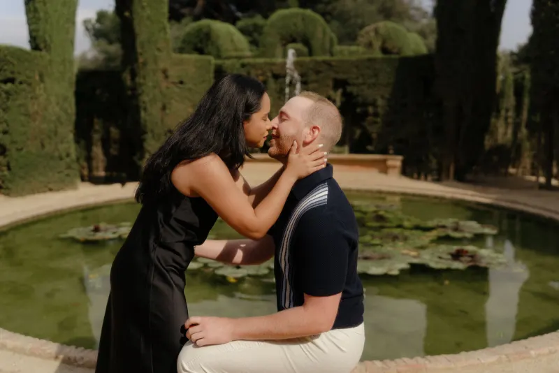 Joyful couple embraces by a lily pond after a surprise proposal, captured during a professional photoshoot in the garden.