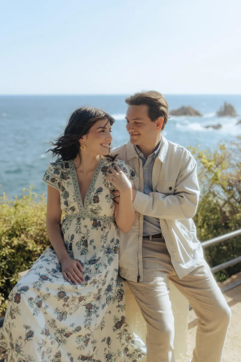 Joyful couple embraces by the seaside, celebrating their engagement during a surprise proposal photoshoot.
