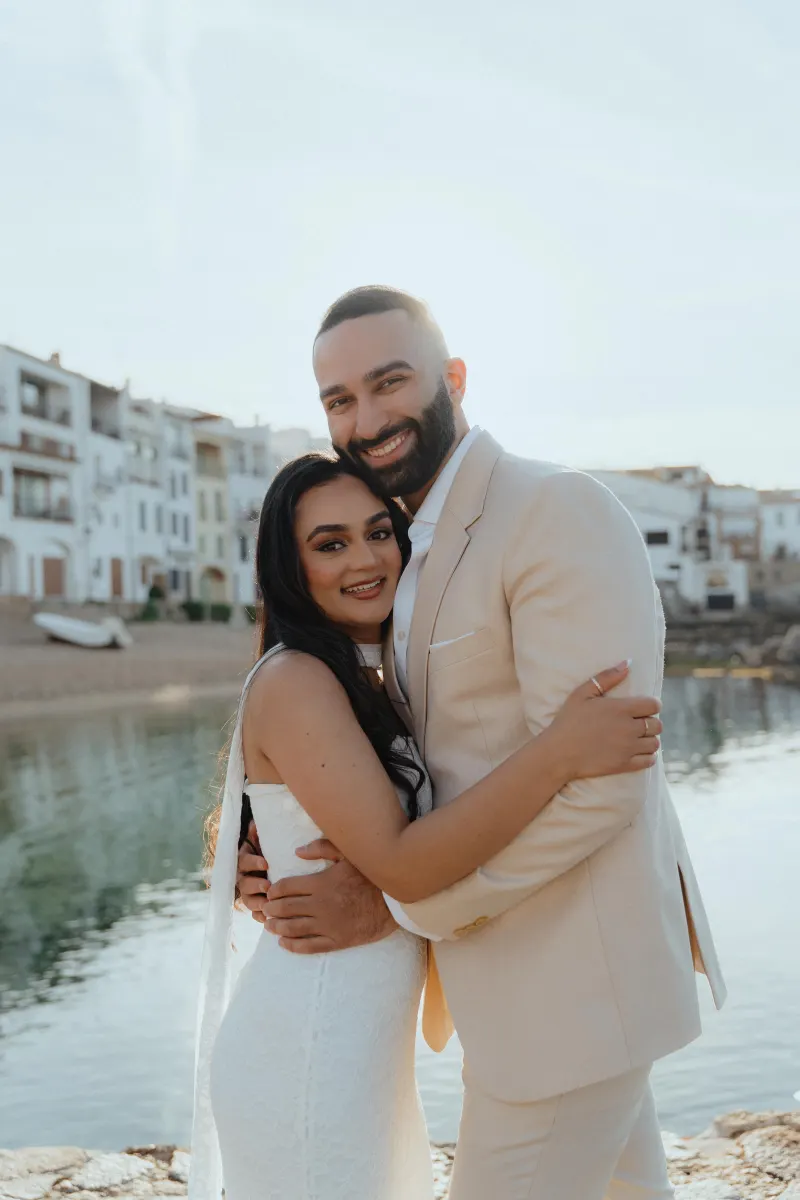 Joyful couple embraces by the water after a surprise proposal photoshoot in a charming coastal village.