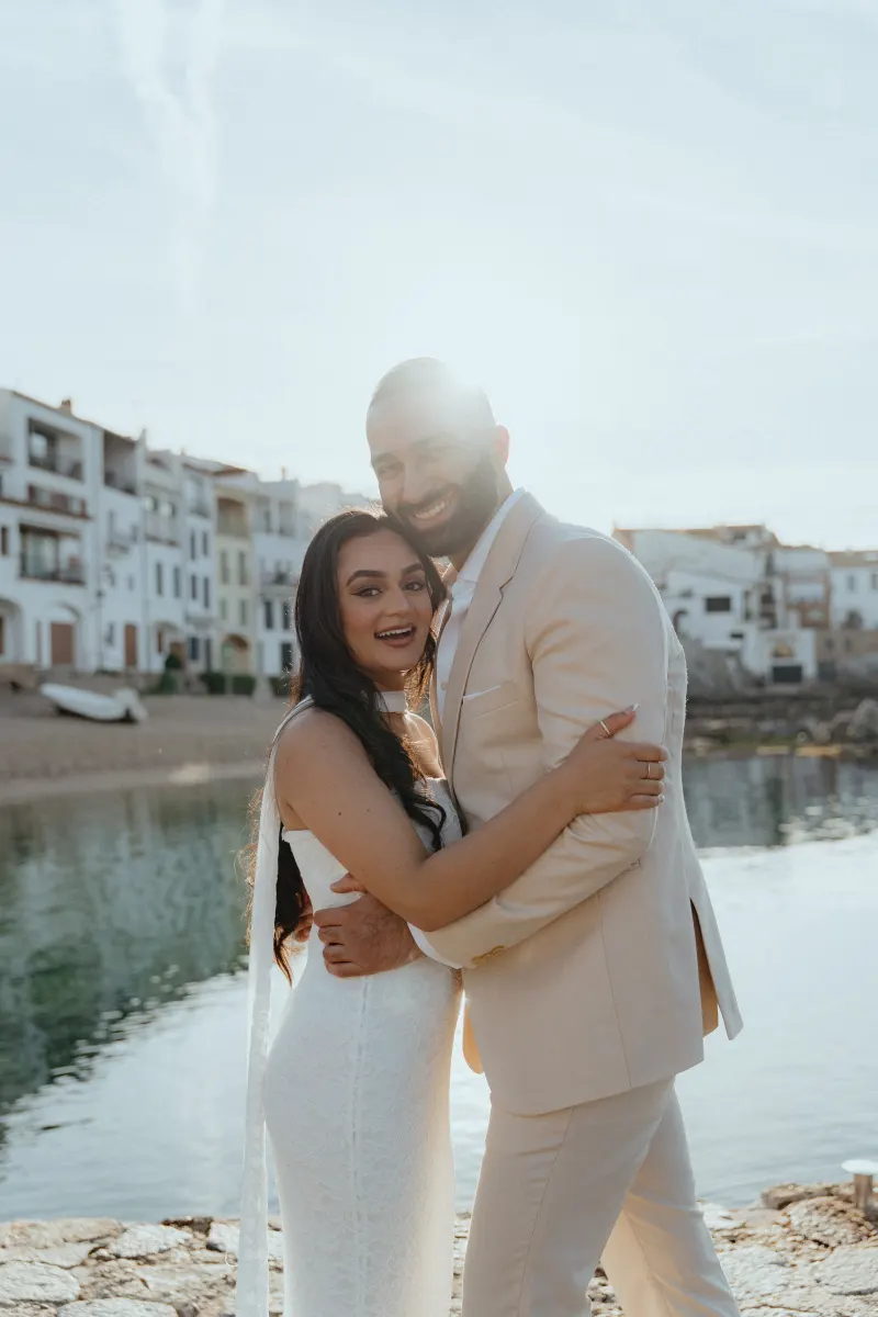 Joyful couple embraces by the waterfront after a surprise proposal photoshoot in a charming coastal village.