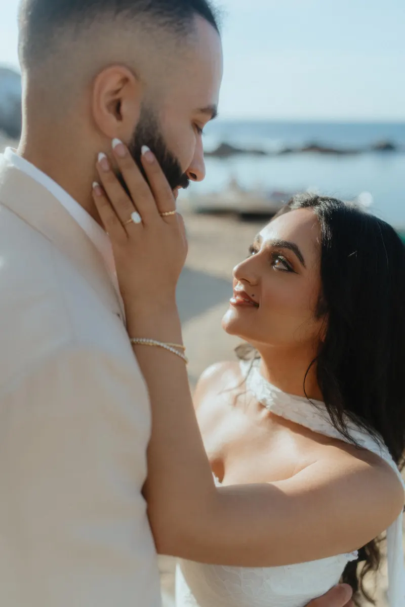 Joyful couple embraces on the beach after a surprise proposal, capturing love and emotion in a candid photoshoot.