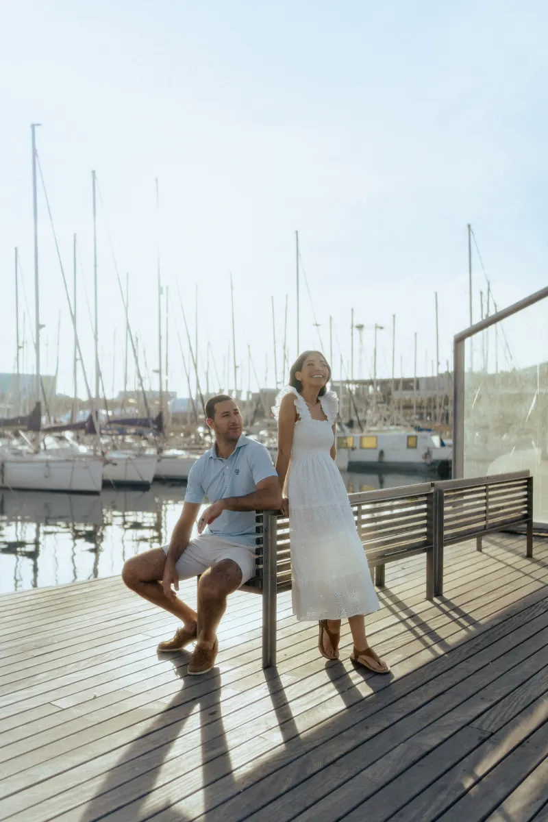 Joyful couple enjoying golden hour on a marina boardwalk, part of a couples & engagements photoshoot session.