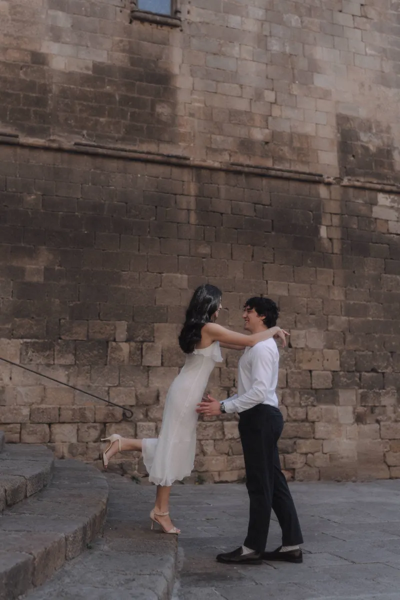 Joyful couple shares a playful embrace on stone steps during a couples & engagements photoshoot in the historic city.