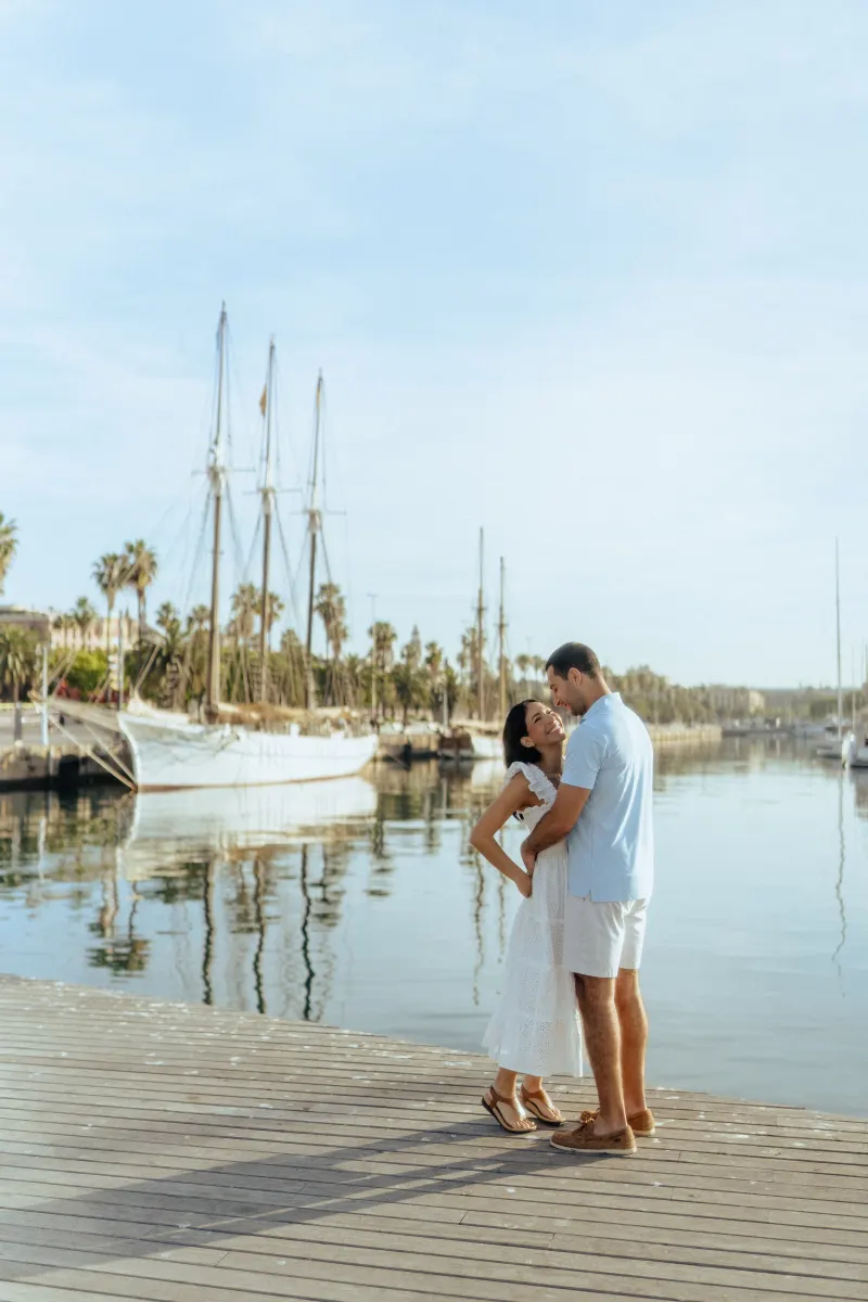 Laughing couple embraces on a sunny marina boardwalk, captured during a couples & engagements photoshoot.
