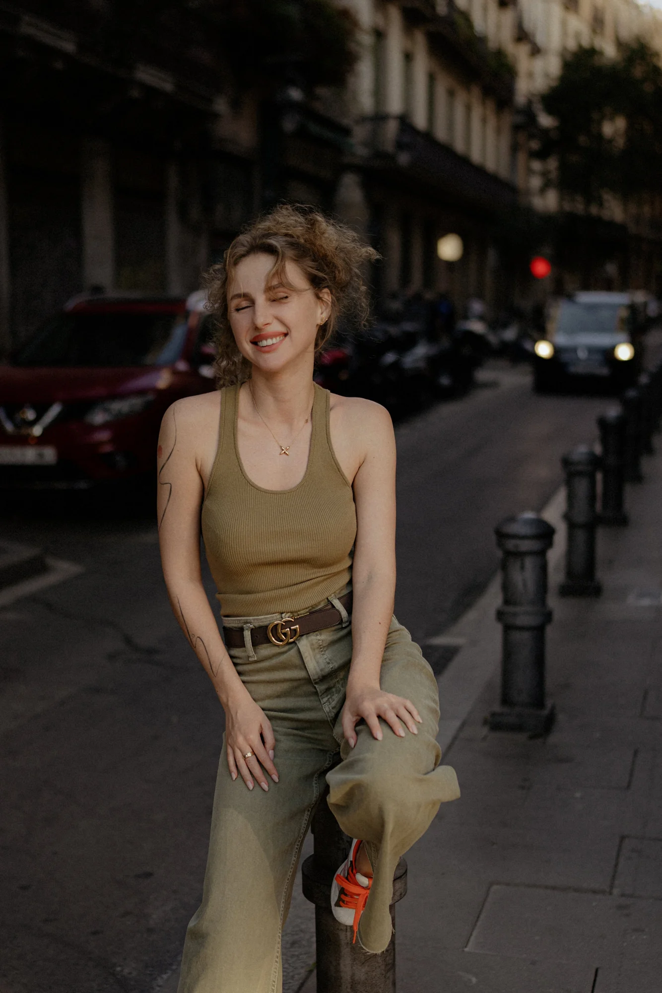 Laughing woman sits on a city bollard during a Vacation Portraits shoot, capturing a joyful travel memory.