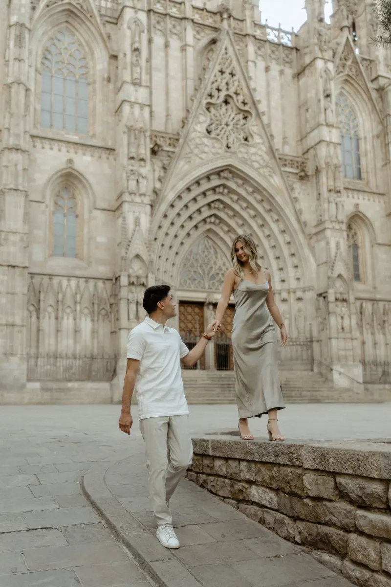 Man helping his partner step down from a ledge outside Barcelona’s cathedral during a Vacation Portraits photoshoot.