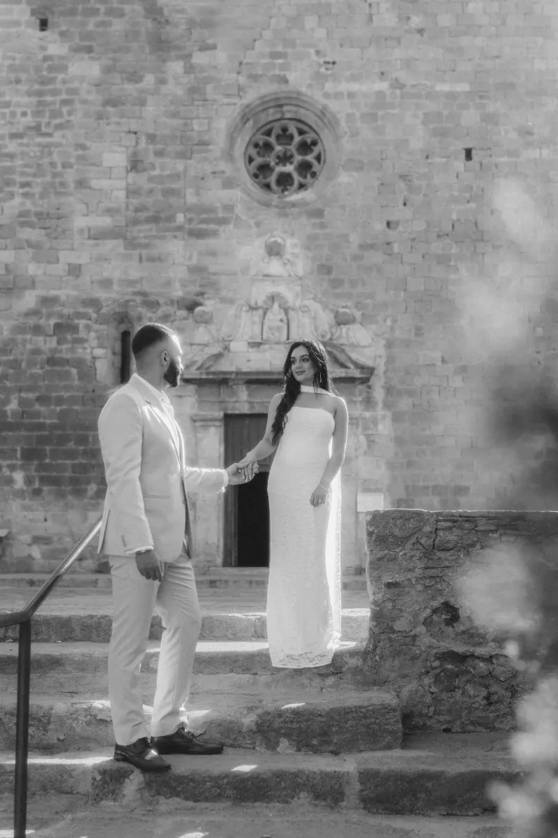 Man in a light suit gently holds his fiancée’s hand on ancient stone steps during a surprise proposal photoshoot.