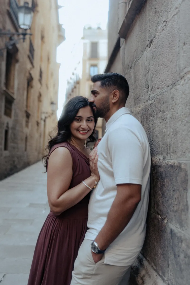 Man kisses his partner’s forehead as she smiles, sharing a tender moment during a couples & engagements shoot in a historic a