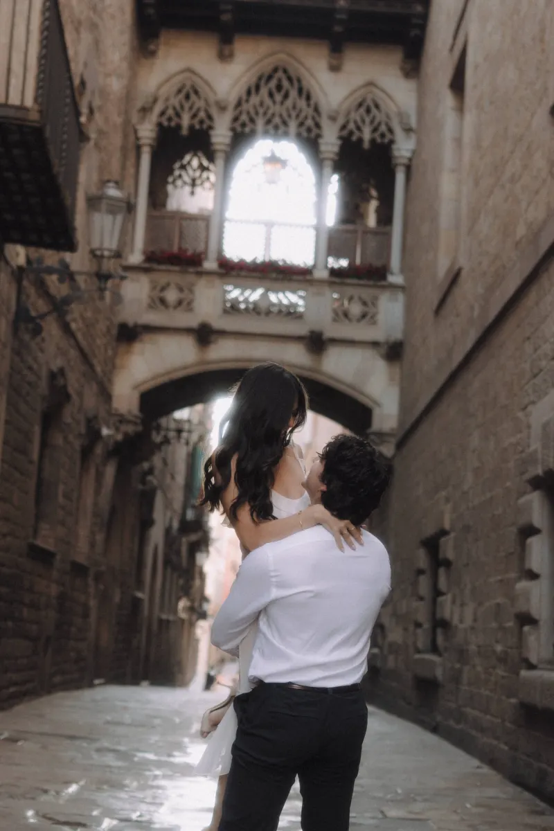 Man lifts his partner in a joyful embrace on a romantic street in Barcelona’s Gothic Quarter during a couples photoshoot.