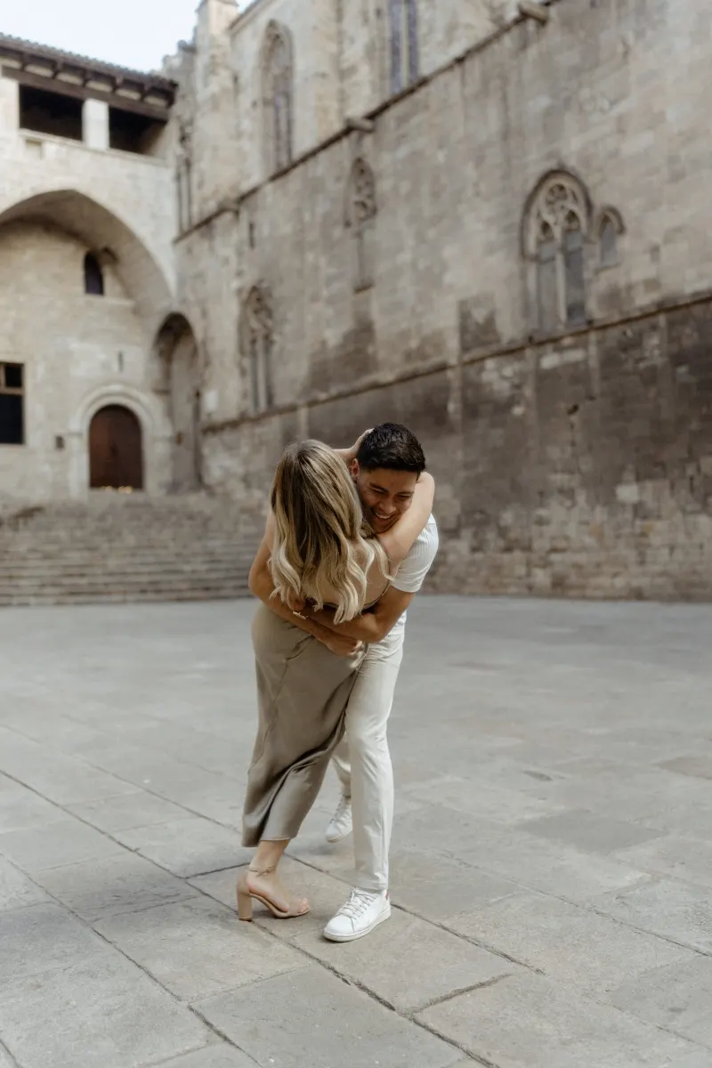 Man playfully lifts his partner in a joyful embrace during a Vacation Portraits session in Barcelona’s historic quarter.