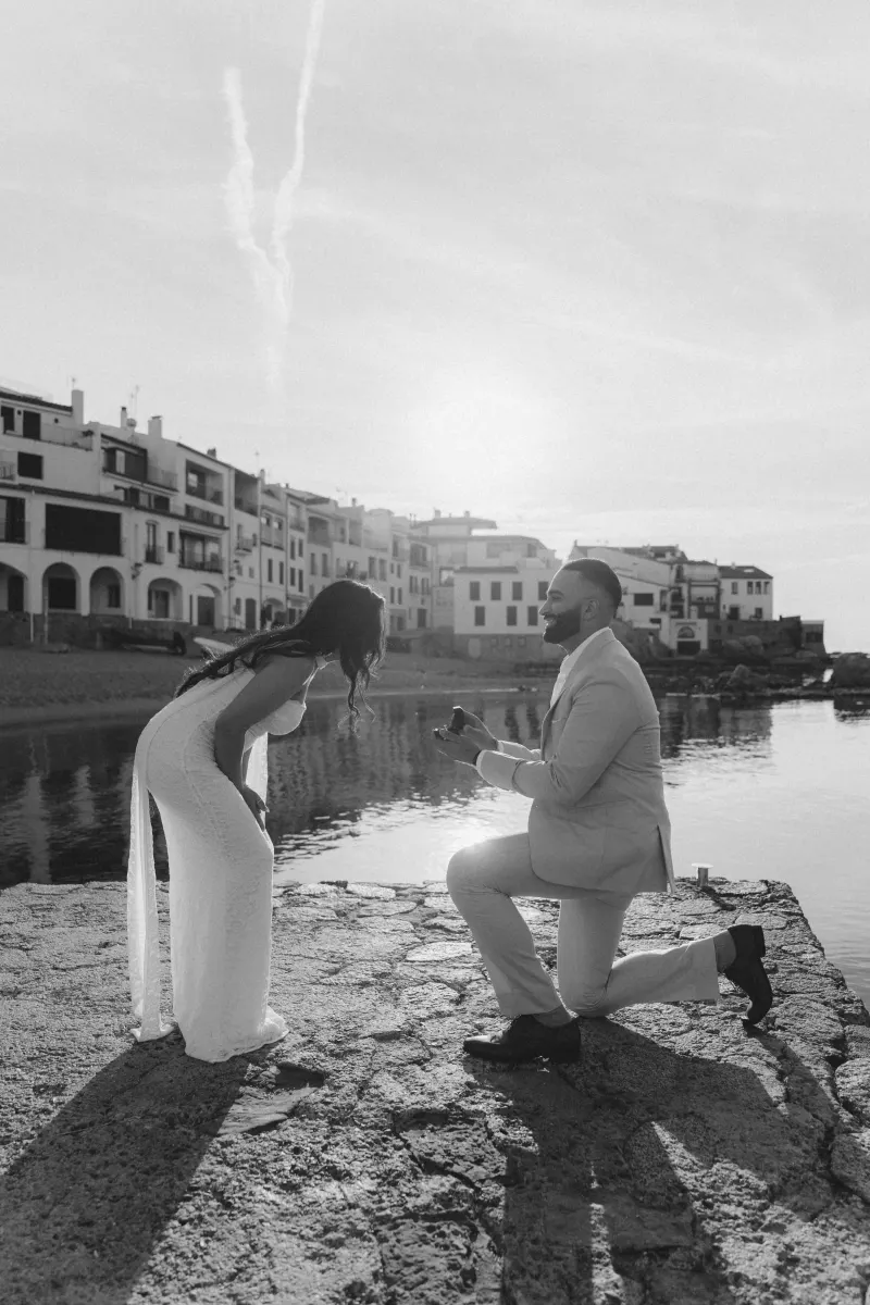 Man proposes to his surprised partner by the waterfront at sunset, captured during a surprise proposal photoshoot.