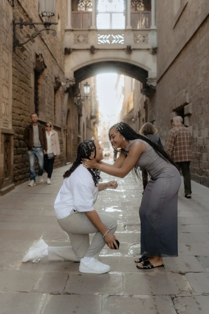 One partner kneels to propose as their loved one smiles with joy in Barcelona’s Gothic Quarter during a surprise proposal sho