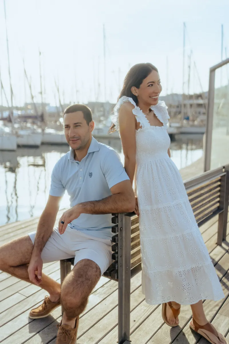 Playful couple enjoying a lighthearted moment on a marina boardwalk during a couples & engagements photoshoot.