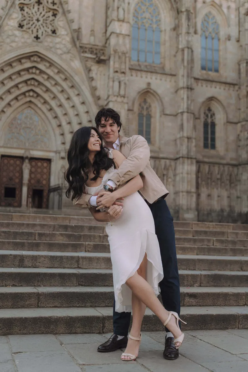 Playful couple laughing together on cathedral steps during a couples & engagements photoshoot in the city.