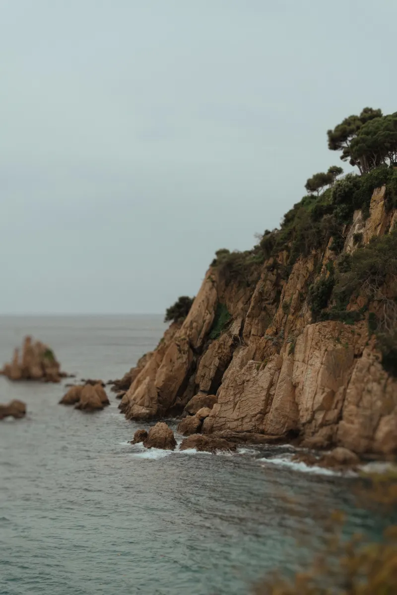 Rocky seaside cliffs with lush greenery, perfect backdrop for a surprise proposal photoshoot by the ocean.