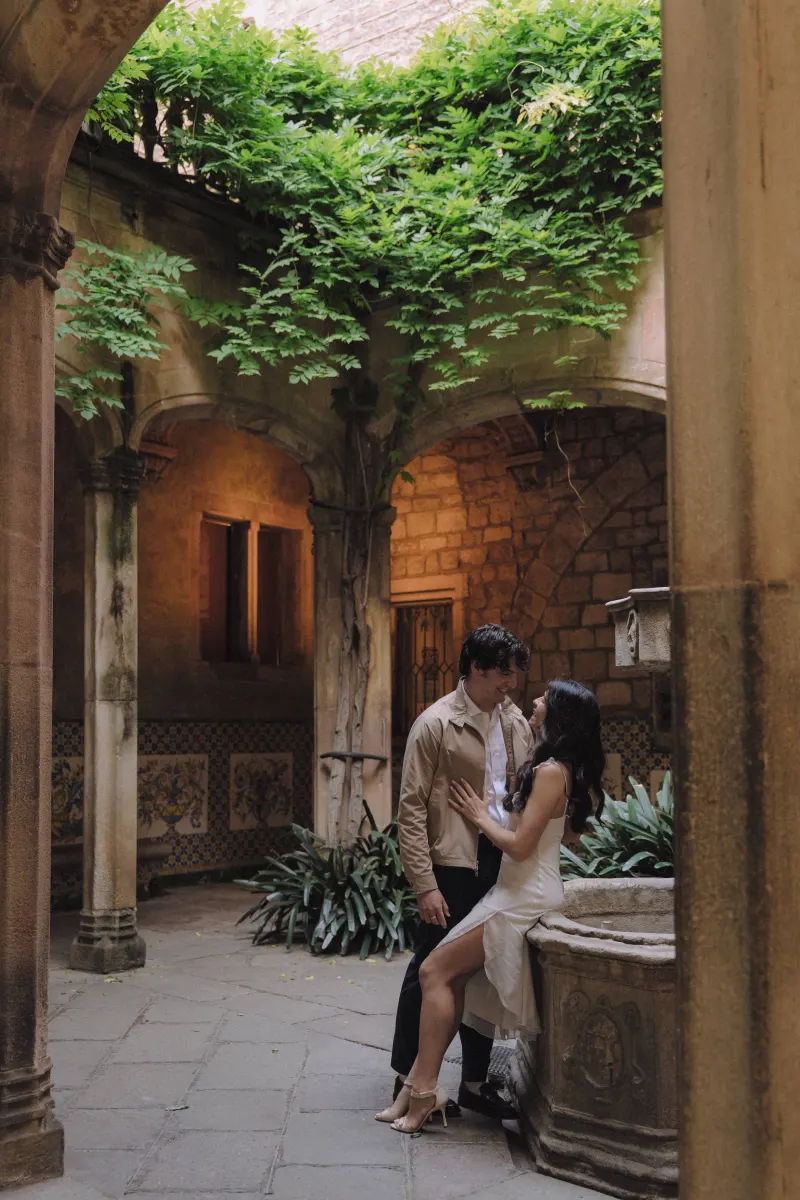 Romantic couple sharing an intimate moment in a lush, historic courtyard during a couples & engagements photoshoot.