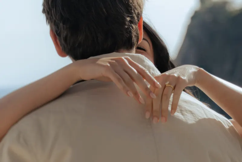 She embraces her fiancé by the sea, engagement ring gleaming, during a surprise proposal photoshoot.