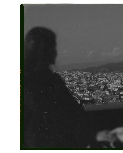 Silhouetted couple gazes over a sprawling cityscape, capturing a quiet moment during an engagement session.