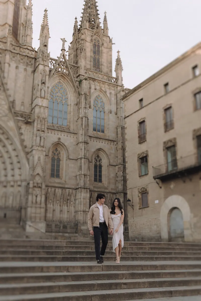 Smiling couple descending cathedral steps hand in hand during a couples & engagements photoshoot in the city.