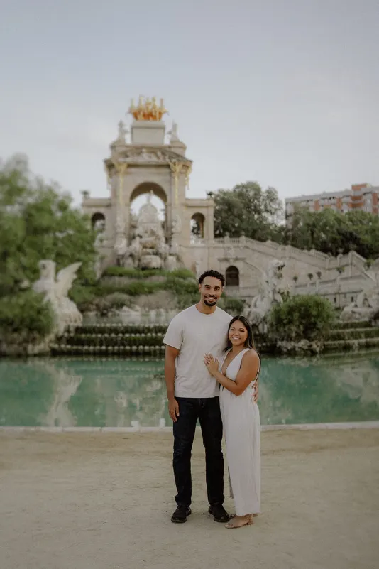 Smiling couple embraces by the fountain at Parc de la Ciutadella during a romantic couples & engagements photoshoot.