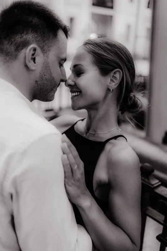 Smiling couple sharing a close, loving moment during a couples & engagements photoshoot in a softly lit indoor setting.