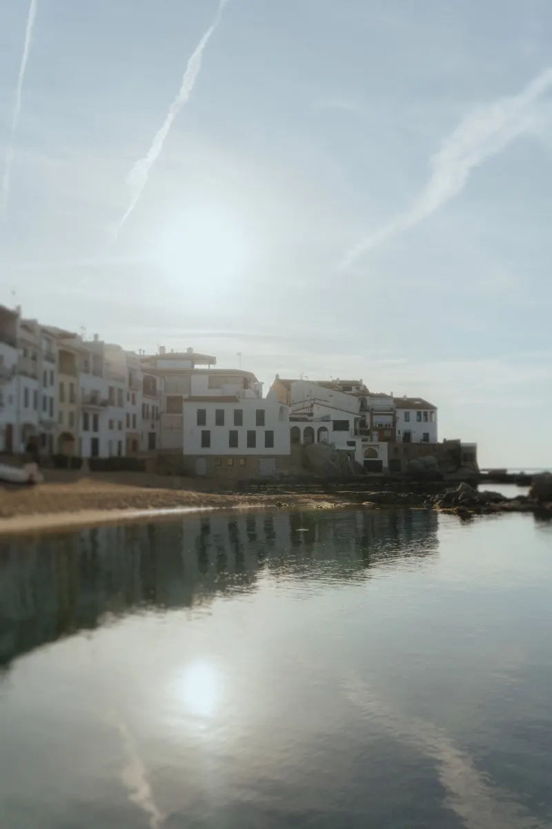 Soft morning light over a quiet coastal village, calm water reflecting white buildings, perfect for a surprise proposal photo